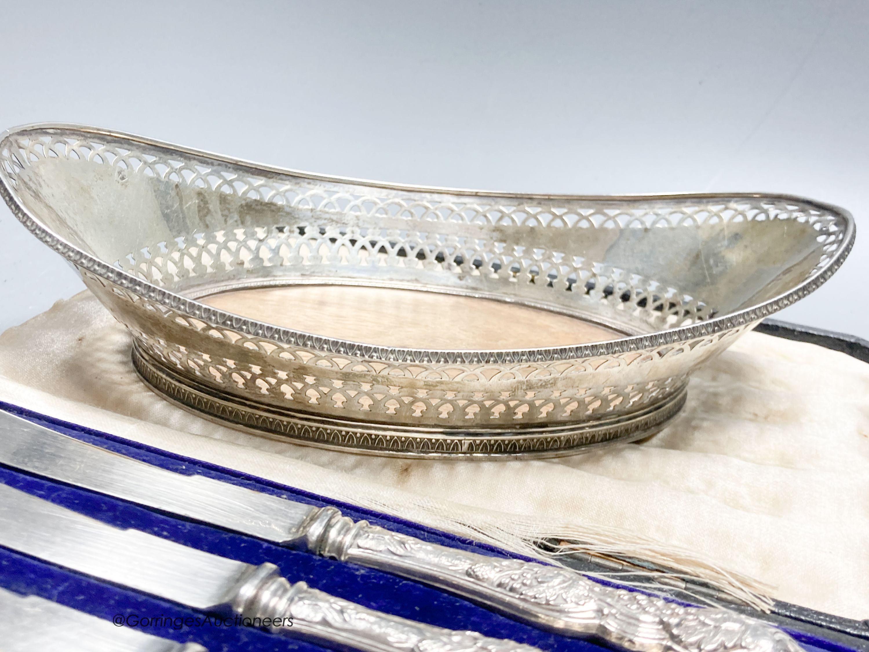 A George V silver two handled butter dish, with blue glass liner, a white metal basket, a pair of Victorian shell dishes, a French white metal dish, white metal toast rack and cased tea knives.